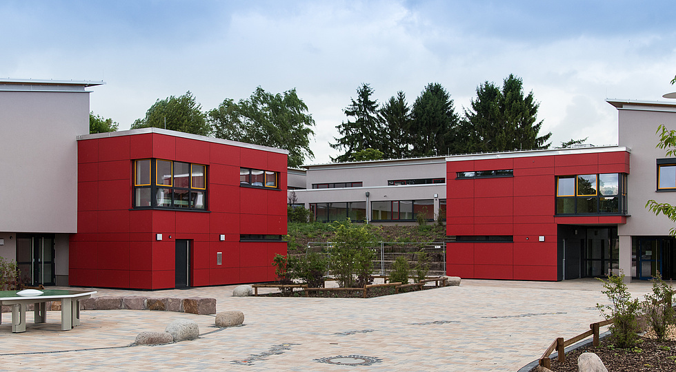 Ansicht des Schulgebäudes mit moderner, roter Fassade