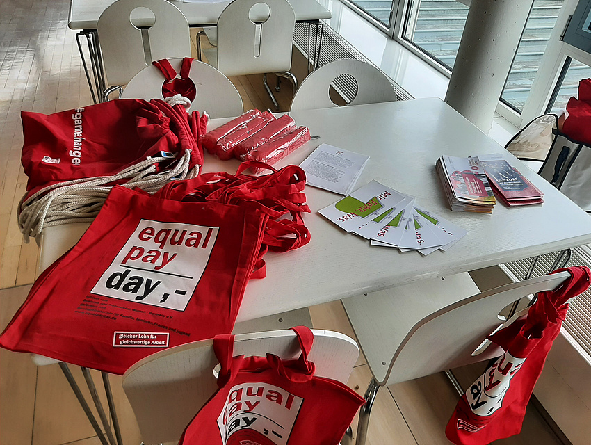 Rote Taschen und Flyer liegen auf einem Tisch. 